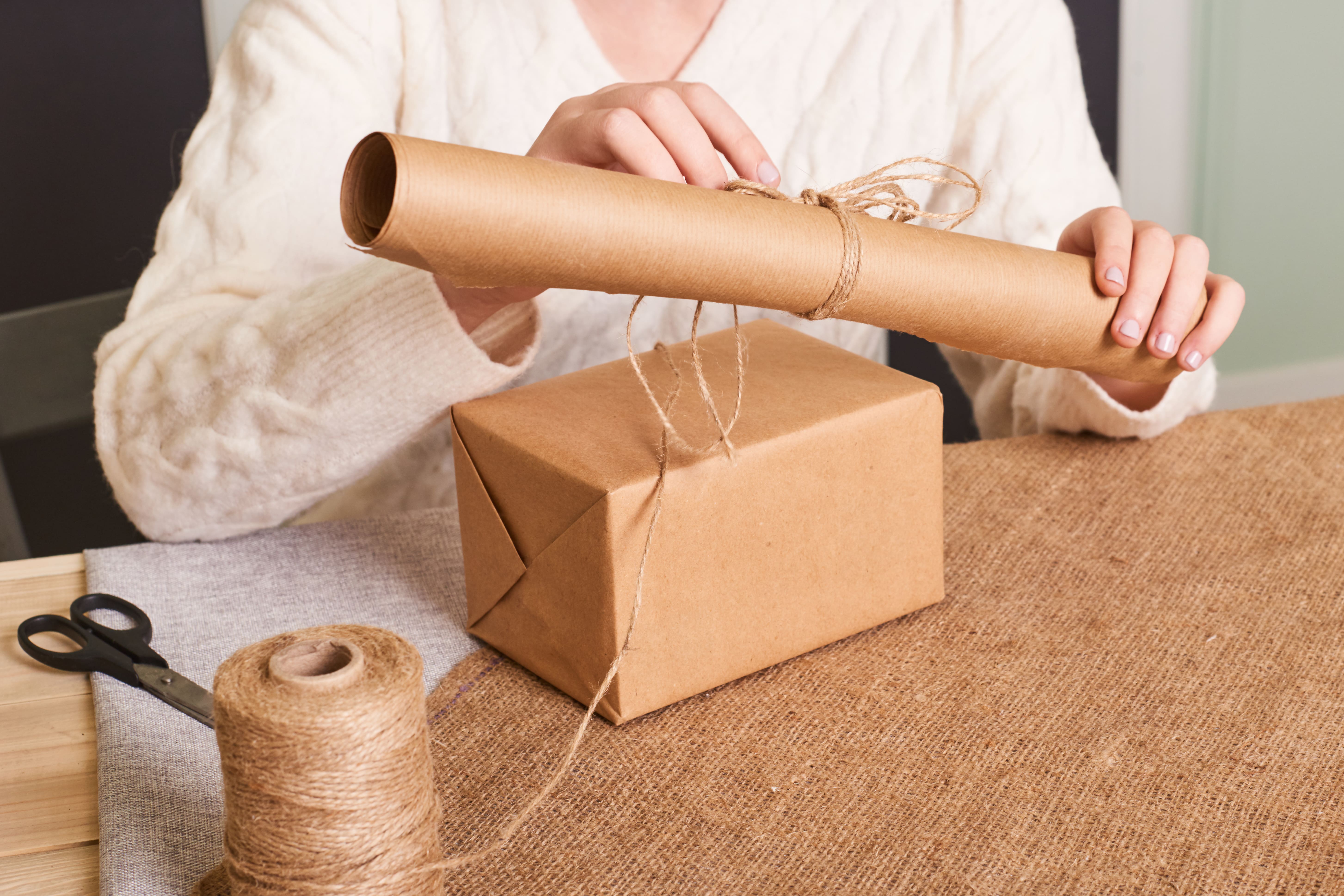 focus-woman-s-hands-white-knitted-sweater-packaging-box-craft-wrapping-paper-natural-twine-happy-holiday-present-surprise-gifts-boxing-day-min